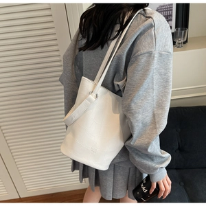 Close-up of white bucket bag featuring luxury crocodile texture and embossed MER PAI logo