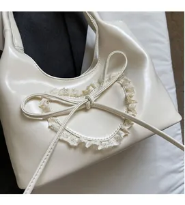 Dettaglio borsa a mano bianco crema in similpelle con cuore in pizzo e fiocchetto