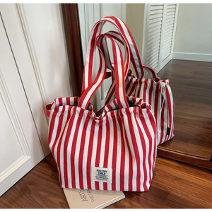 Detail view of red and white striped canvas tote bag with drawstring closure and brand label