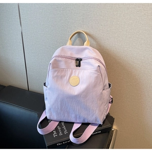 Detail of light purple nylon backpack with leather handle on minimalist book background