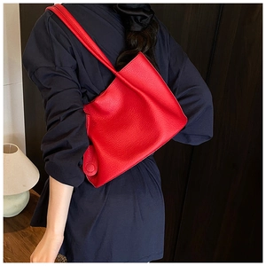 Detail of red lychee textured leather tote bag featuring unique folded side design