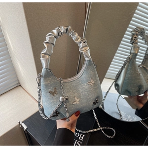 Detail of blue denim crossbody bag with metallic scrunchie handle and butterfly accents