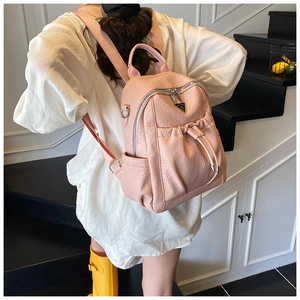 Detail of pink pebbled PU leather backpack with a decorative metal triangle logo