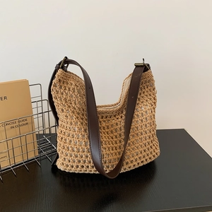 Close-up of woven net hobo bag with adjustable brown leather strap and metal buckle