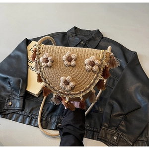 Detailed view of woven straw bucket bag with floral accents and brown silk fringe tassels