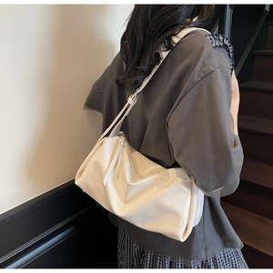 Tragefoto der cremeweißen Pillow-Bag mit glänzender Oberfläche an einem Treppenaufgang