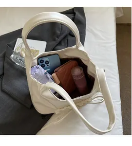 Vista dall'alto che mostra l'ampio interno di una borsa tote bianca con oggetti quotidiani
