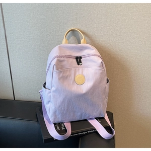 Close-up of light purple nylon backpack with yellow leather handle and circular logo