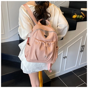 Pink lychee grain faux leather backpack with silver triangular plaque on street scene