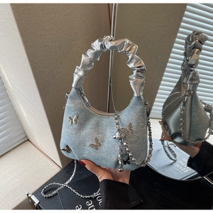 Detail of light blue denim hobo bag with silver butterfly charms and crinkled handle
