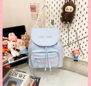 Detail of light blue nylon backpack featuring embroidery and decorative beaded handle