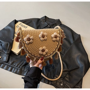 Detail of woven straw bucket bag with crochet flowers, golden sequins and long tassels