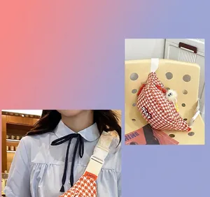Détail du sac bandoulière orange à motif pied-de-poule avec étiquette STAY et pompon