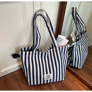 Detail of blue and white striped canvas tote bag with woven label and long handle