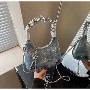 Detail of blue denim shoulder bag with silver butterfly charms and metallic strap