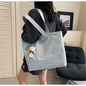 Close-up of light blue tote bag with H.SHAN logo and cute white bear charm detail