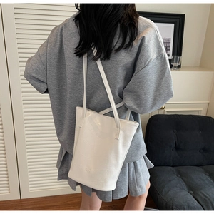 Rear view of white faux leather tote bag with crocodile texture on a fashion model