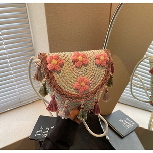 Detail of bohemian straw bucket bag featuring 3D crochet flowers and colorful fringe tassels