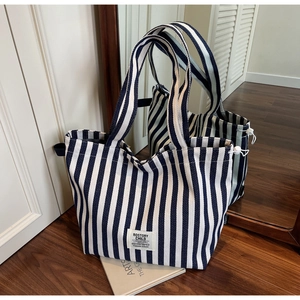 Detail of blue and white striped canvas tote bag with drawstring and brand label