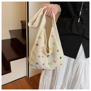 Close-up of beige knit tote bag with colorful beads and detailed woven texture