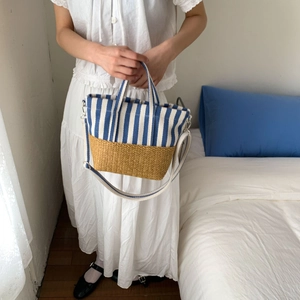 Detail of canvas striped tote with straw base and adjustable crossbody strap