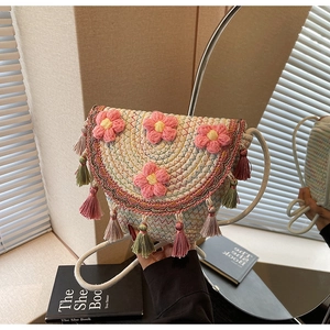 Detail of bohemian knit bucket bag with crochet flowers and colorful tassels