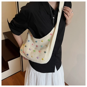 Detail of cream knitted hobo bag featuring colorful beads and hollow weave texture
