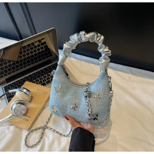 Detail of light blue denim bag with metallic butterfly charms and a silver scrunchie handle