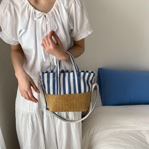 Detail of striped canvas and straw patchwork tote bag with adjustable shoulder strap