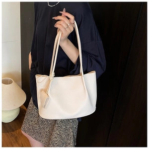 Close-up of creamy white litchi pattern leather tote bag worn by model on shoulder