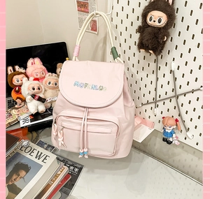 Close-up of pink travel backpack featuring colorful embroidery and decorative rope handle