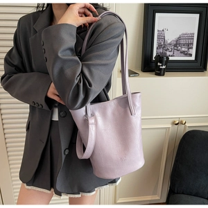 Detail of light purple crocodile embossed leather bucket bag with brand logo and strap