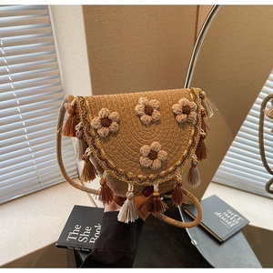 Detail of woven crossbody bag with floral accents, brown fringes and rope strap