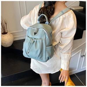 Detail view of light blue lychee pattern leather backpack with drawstring and metal logo