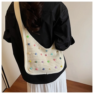 Detail of beige crochet shoulder bag with multi-colored beads on black shirt background