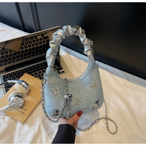 Detail of light blue denim texture bag with silver butterfly and pleated cloud handle