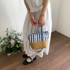 Detail of canvas stripe and straw patchwork tote bag with adjustable shoulder strap