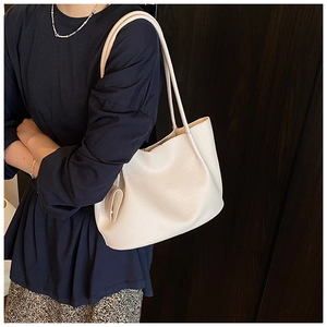 Detailed view of beige litchi pattern leather tote bag worn by model over shoulder