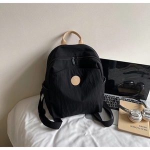 Detail view of black nylon backpack with brown handles and front pocket for daily commute