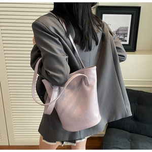 Detail of light purple crocodile embossed bucket bag styled with a grey blazer
