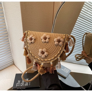 Detail of beige woven straw bucket bag featuring crochet flowers and fringe tassels