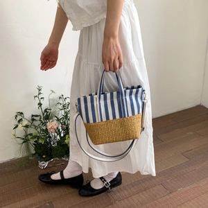 Detail of blue striped canvas and straw woven handbag with detachable shoulder strap