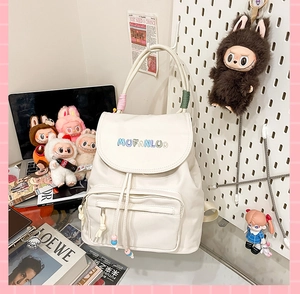 Detail of white backpack featuring colorful embroidery and woven candy-colored handles