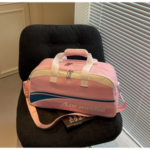 Pink sports travel bag with brand logo and striped detail on a dark velvet chair