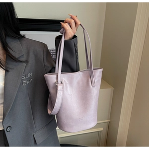 Detail of lavender crocodile-embossed bucket bag with metallic hardware on a blazer