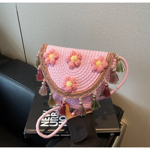 Detail of pink woven bucket bag with 3D floral accents and colorful tassels charm
