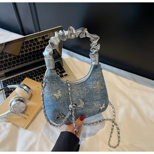 Close-up of blue denim dumpling bag with silver butterfly and metallic chain strap