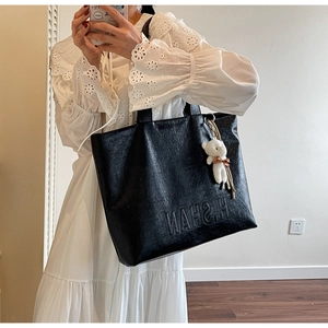 Detailed view of black pebbled leather tote bag with H.SHAN lettering and cute bear charm