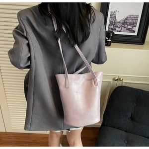 Detail of light purple crocodile embossed bucket bag with adjustable strap and embossed logo