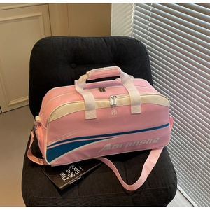Detailed view of pink sports duffel bag with white leather accents and logo on a velvet chair